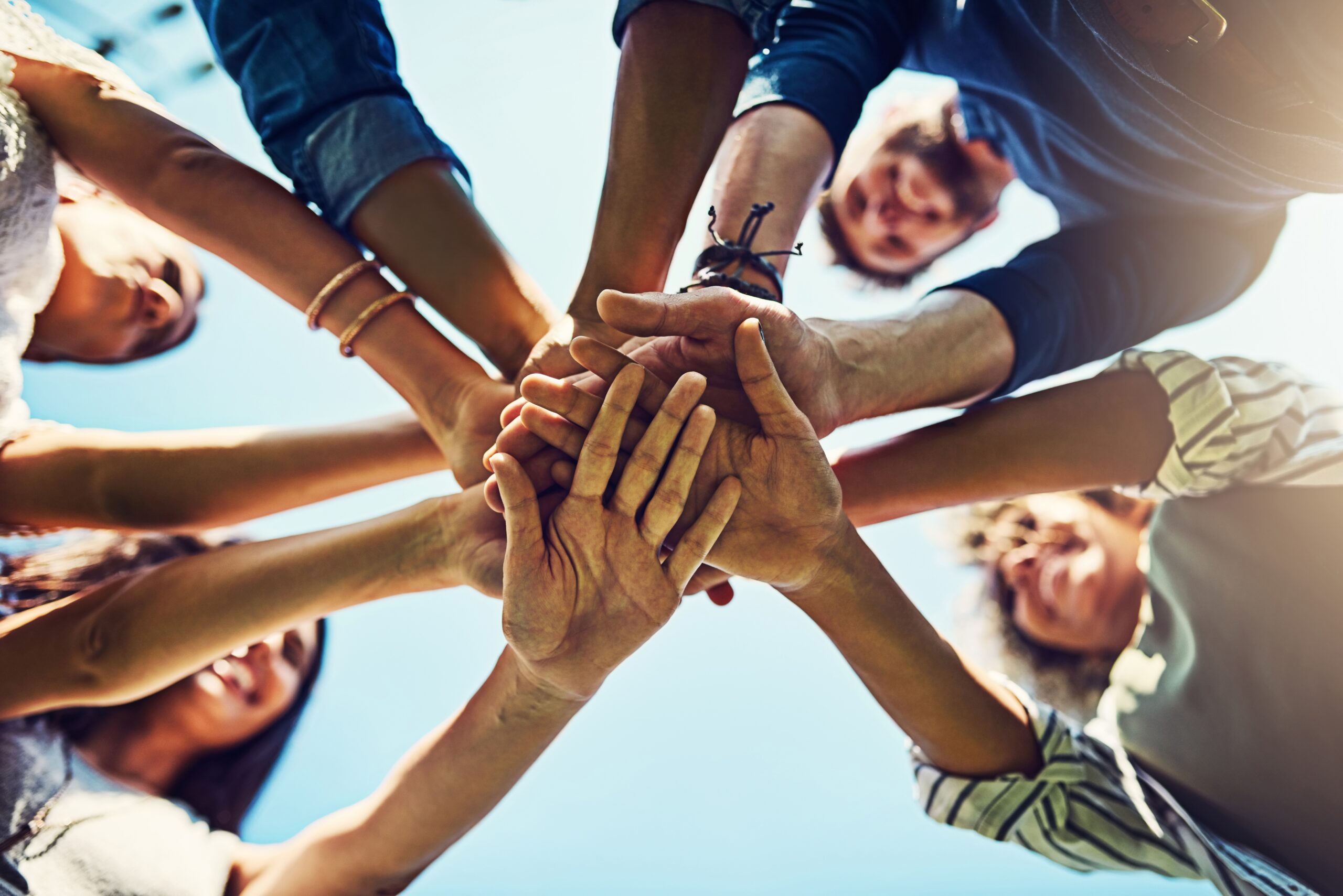 A group of diverse hands stacked together in a gesture of unity, illustrating teamwork. This image represents AZEE Training team building course on High-Performing Teams.