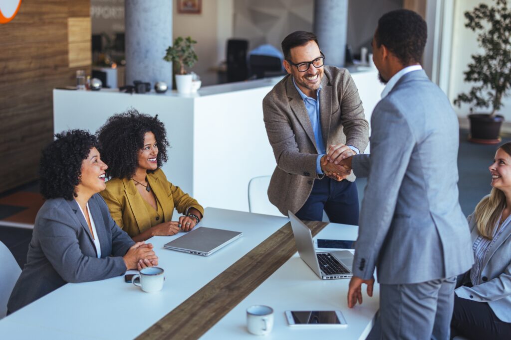 Professionals shaking hands and collaborating, illustrating AZEE Training Interpersonal Skills course for Better Teamwork and Conflict Resolution.